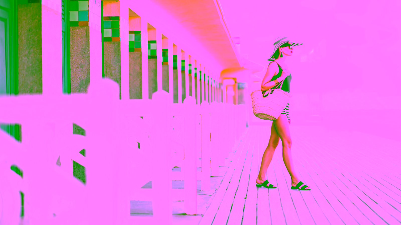 Woman walking on a beach boardwalk with a straw bag