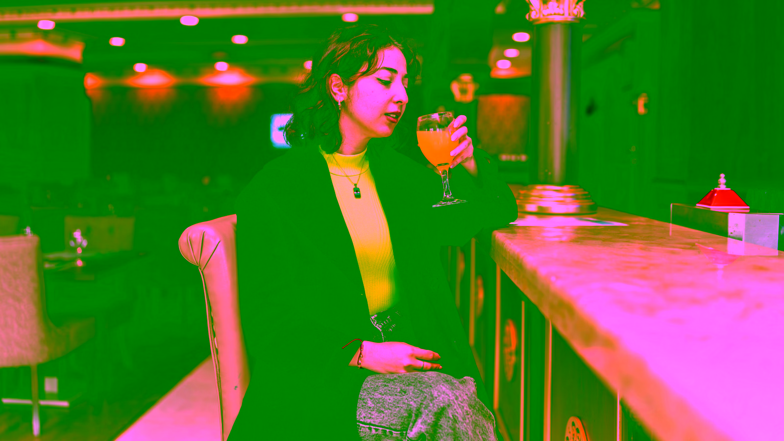 Woman drinking orange cocktail at bar