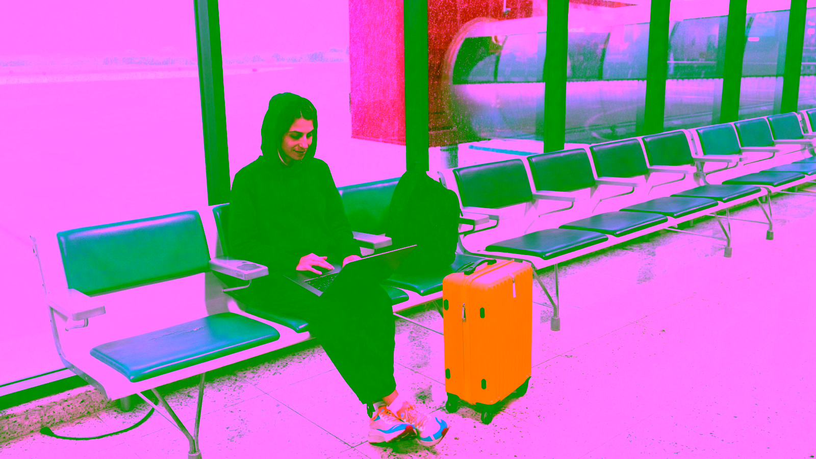 person working on laptop with suitcase in airport