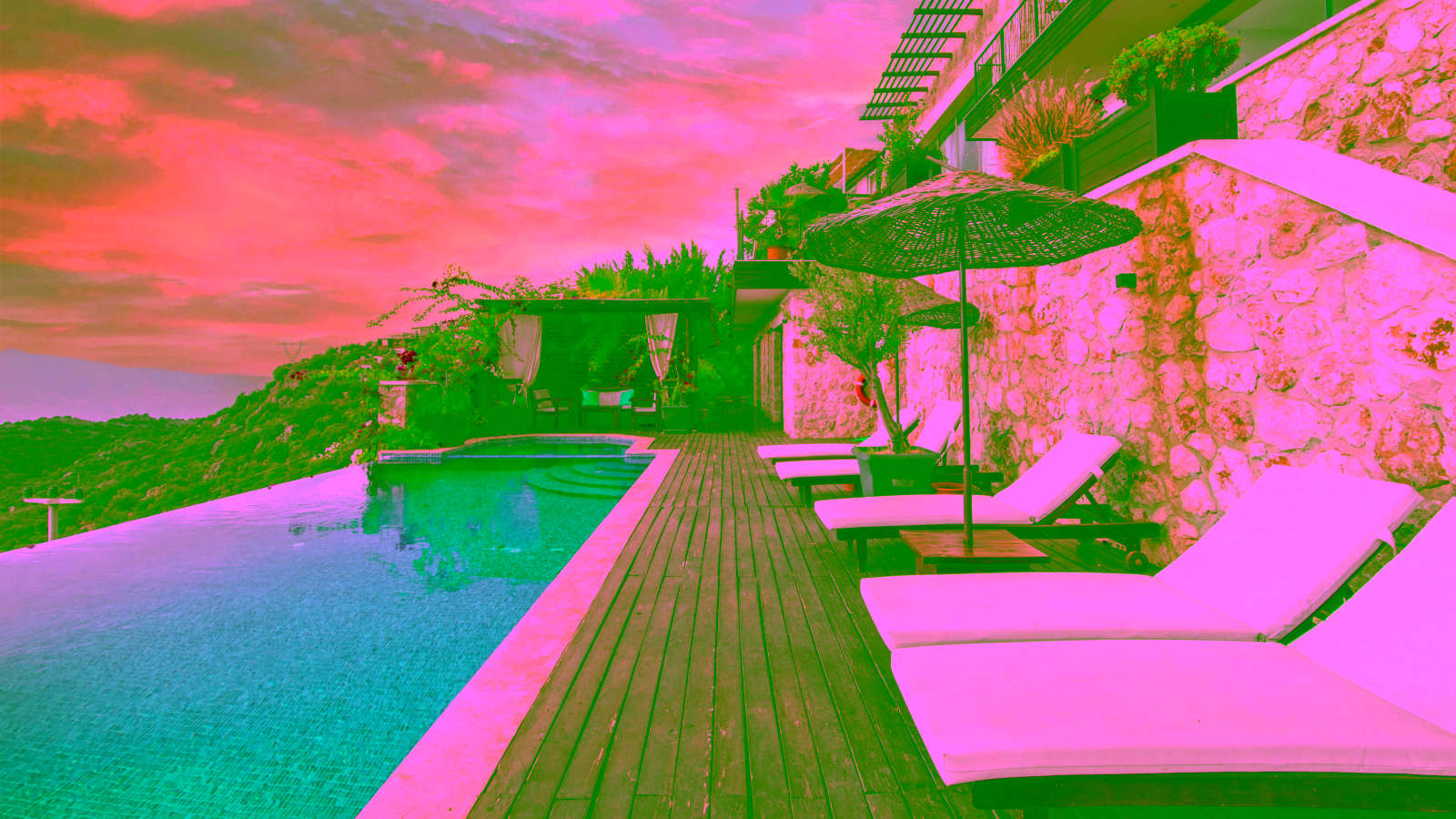 Infinity pool with lounge chairs at luxury hillside resort at sunset