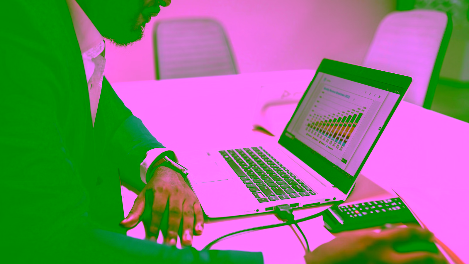 Businessman reviewing charts on laptop with calculator on desk.