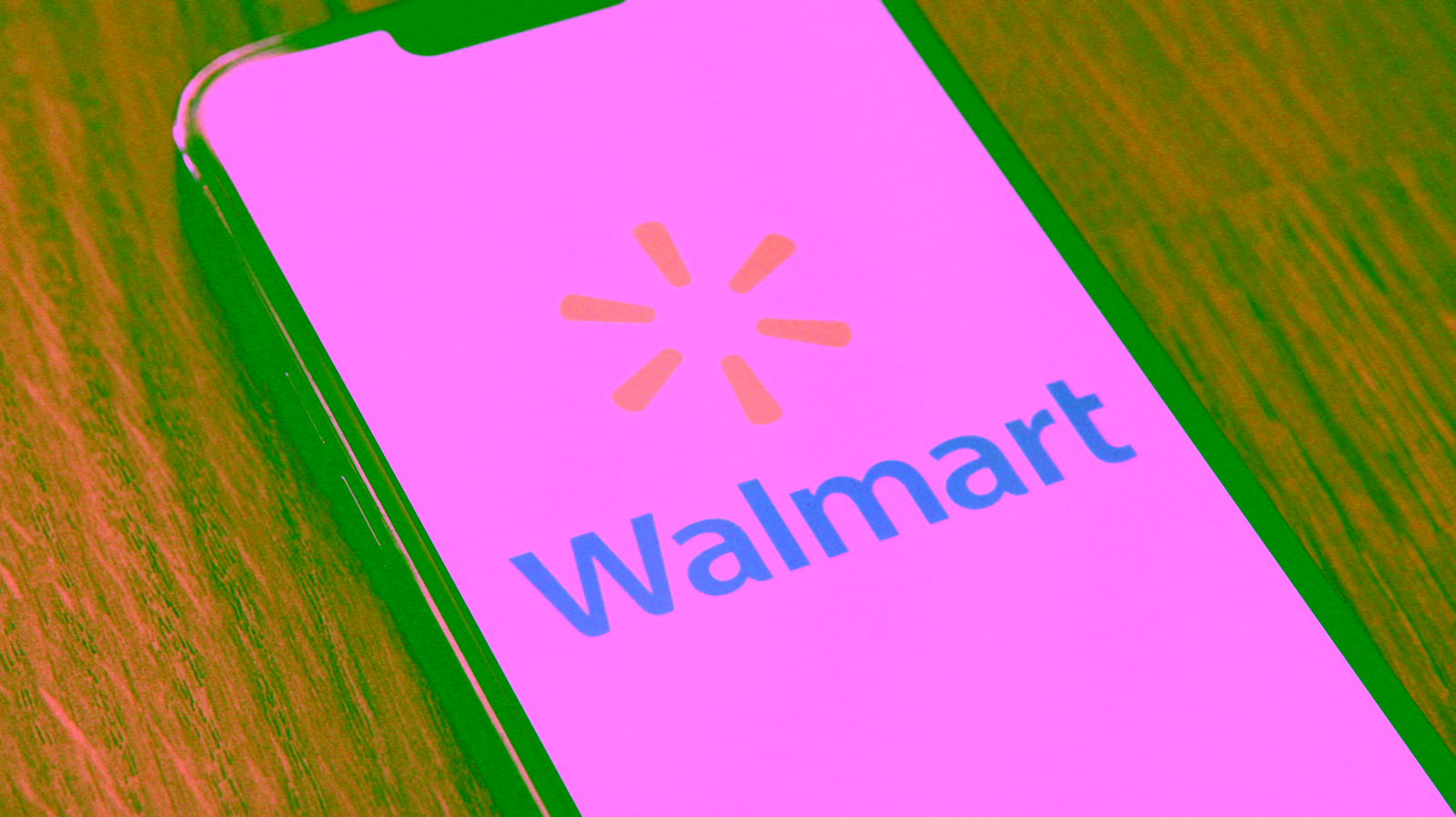 Smartphone displaying Walmart logo on screen on wooden surface